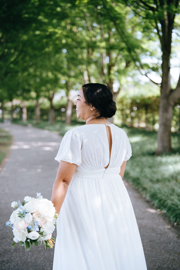 Back of bride as she walks away smiling and holding a bouquet