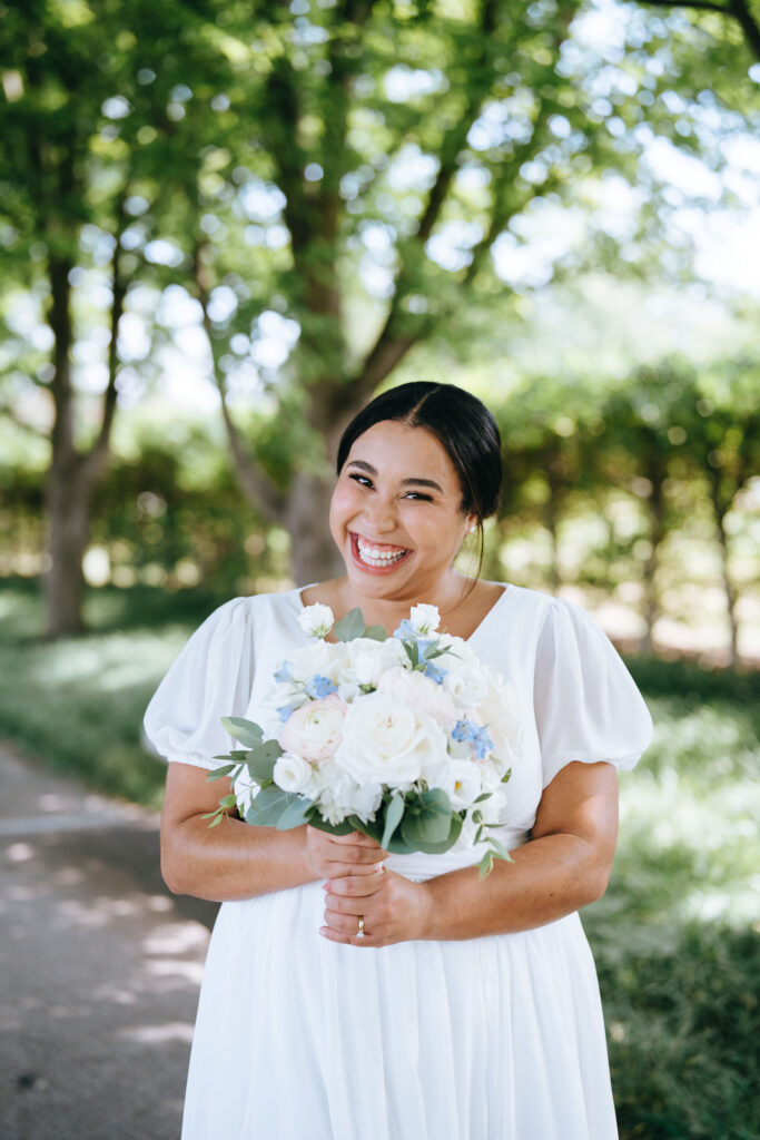 bride smiling while holding up her wedding bouquet