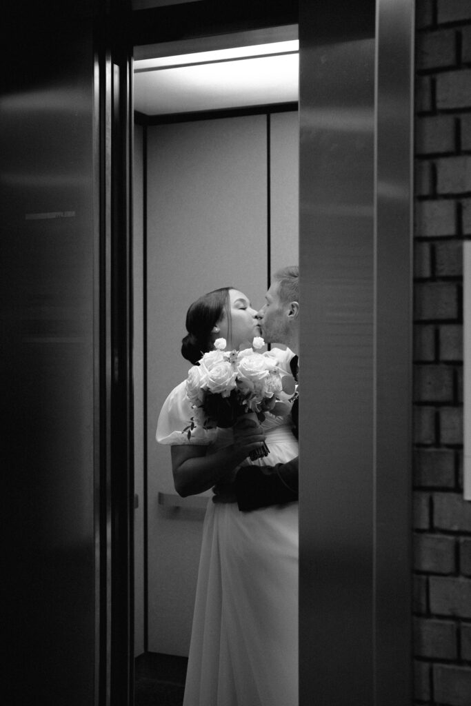 bride and groom kissing in the elevator as the doors close