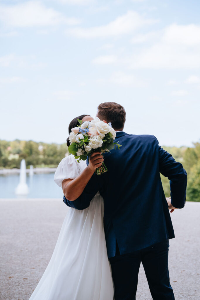 wedding couple kissing behind wedding bouquet