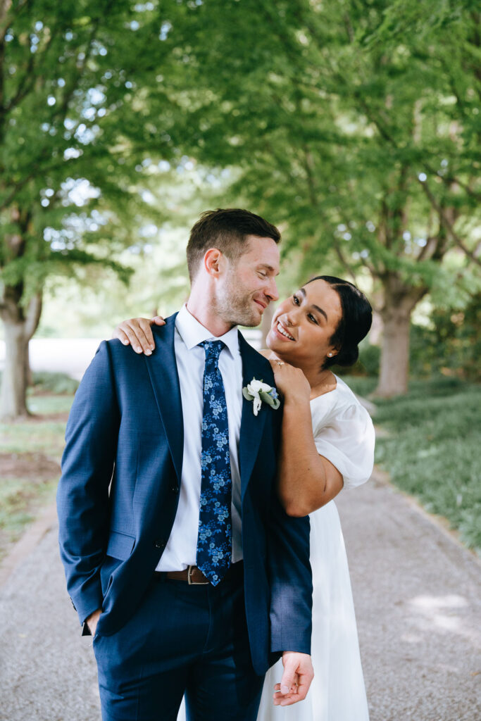 A married couple staring in each others eyes while the bride hugs the groom from behind