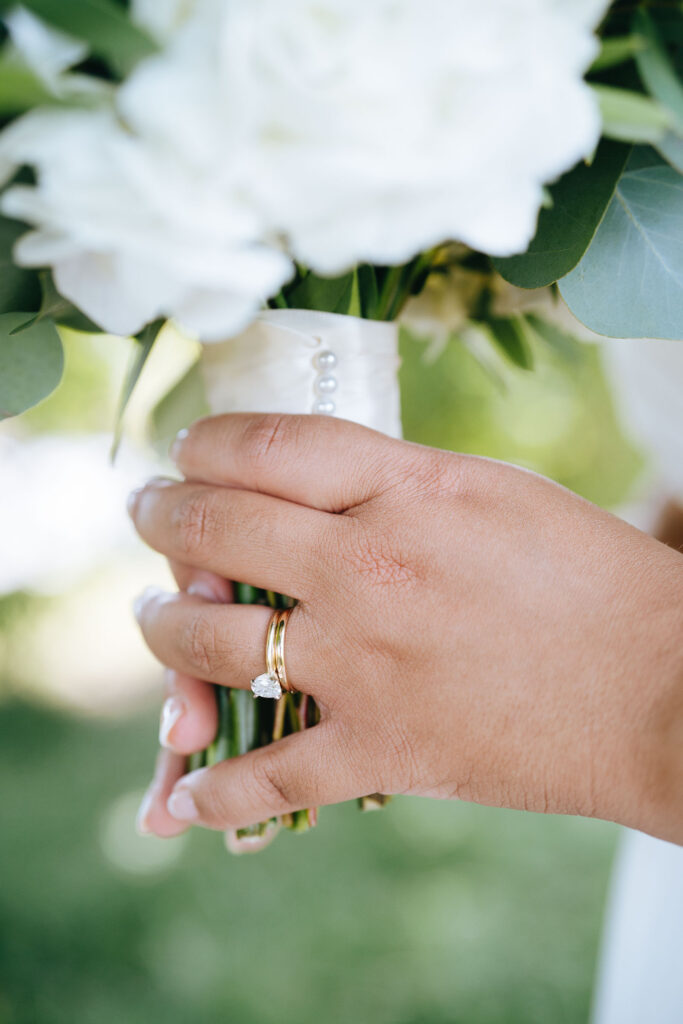 Close-up photo of bride's hand while holding wedding bouquet