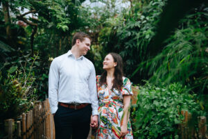 Couple standing side by side holding hands and smiling at each other