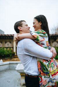 Man lifting fiancee in the air at the mobot garden while it's raining