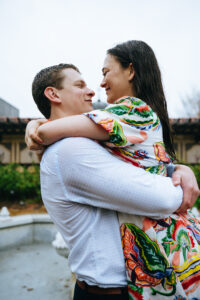 Man lifting fiancee in the air at the mobot garden while it's raining