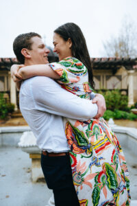 Man lifting fiancee in the air at the mobot garden while it's raining