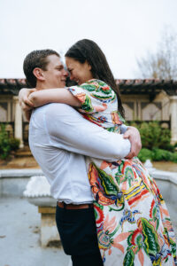 Man lifting fiancee in the air at the mobot garden while it's raining
