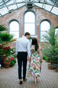 Newly engaged couple holding hands as they walk through the mobot garden