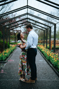 Couple staring into each others' eyes with a row of tulips on either side of them